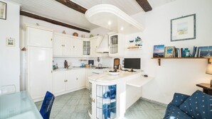 Een moderne keuken met witte kasten, een centraal eiland met blauwe glazen deuren en een zithoek met een blauwe bank.