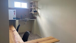 A small kitchenette with a window, a sink, and a wooden table. - Ceo Studio Premium 4 | Comfort and Style close to everything (Aracaju)
