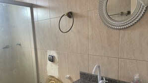 A bathroom with a granite sink, a mirror, a towel ring, and a shower door. - Ceo Studio Premium 4 | Comfort and Style close to everything (Aracaju)