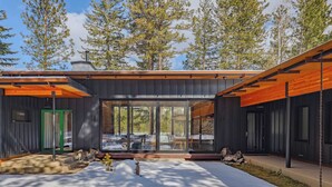 A modern house with a large glass window, a green door, and a wooden deck. - Ursa Minor – Spacious 4BR Retreat near Mazama (Winthrop)