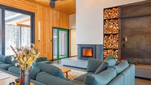 A modern living room with a fireplace, grey sofas, a wooden coffee table, and a vase with dried flowers. - Ursa Minor – Spacious 4BR Retreat near Mazama (Winthrop)