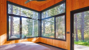 A bedroom with large windows, wooden walls, and a ceiling fan. - Ursa Minor – Spacious 4BR Retreat near Mazama (Winthrop)