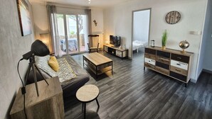 Un salon moderne comprenant un canapé, une table basse, un téléviseur et un meuble en bois.