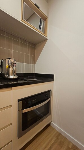 A compact kitchen with a built-in oven and a coffee maker on the countertop. - Terrae Pinheiros (São Paulo)