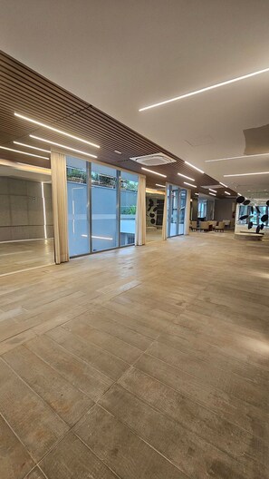 A spacious indoor area with a wooden floor, large windows, and modern lighting fixtures. - Terrae Pinheiros (São Paulo)