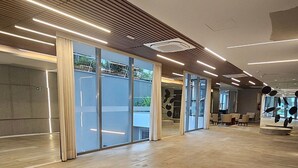 A spacious indoor area with a wooden floor, large windows, and modern lighting fixtures. - Terrae Pinheiros (São Paulo)