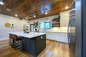 Une cuisine moderne avec un plafond en bois, des meubles blancs et un îlot central.