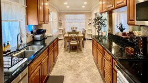 A kitchen with wooden cabinets, a dining table, and a central island. - La Tranquil Escape: Secluded Los Angeles Oasis! (Los Angeles)