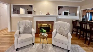 A modern living room with two white armchairs, a small round table, and a fireplace. - La Tranquil Escape: Secluded Los Angeles Oasis! (Los Angeles)