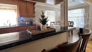A modern kitchen with a central island, wooden bar stools, and a dining area with a table and chairs. - La Tranquil Escape: Secluded Los Angeles Oasis! (Los Angeles)