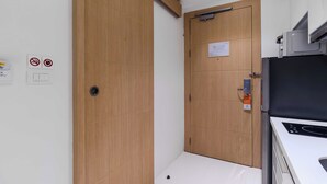A compact kitchen with a microwave, a stove, and a wooden door. - Ocean Breeze1BR Steps from the Sea C244 (Rawai)