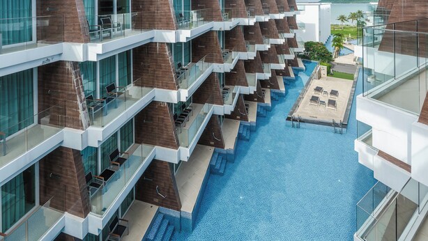 A modern hotel with multiple balconies, a central swimming pool, and a view of the surrounding landscape. - Ocean Breeze1BR Steps from the Sea C244 (Rawai)