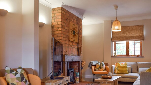 A cozy living room with a brick fireplace, comfortable seating, and a large window with a view. - 3 bedroom accommodation in Kingsthorpe, near Northampton (Kingsthorpe, near Northampton)