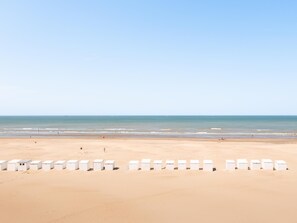 A beach with white beach huts in a row.
