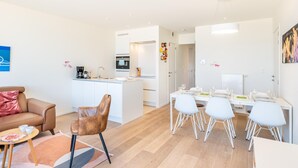 Een moderne woonkamer met een bank, een salontafel en een eethoek met een tafel en stoelen.
