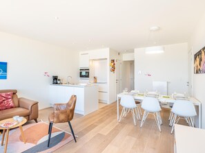 A modern living room with a sofa, a coffee table, and a dining area with a table and chairs.
