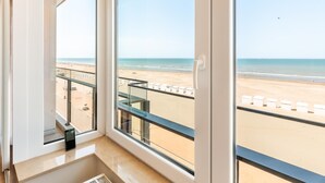 Een kamer met een groot raam met uitzicht op een strand.