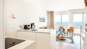 Moderni keittiö, jossa on ruokailutila, merinäköala sekä pieni pöytä ja tuolit.