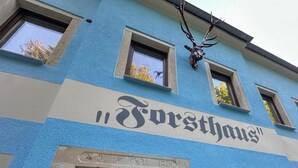 Ein Gebäude mit einem Schild, auf dem 'Forsthaus' steht, und einer Tür mit der Aufschrift 'Nr. 9, 0:20, 1870'.