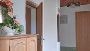 Een houten kast met een spiegel, een bloevas en een groene kaars.