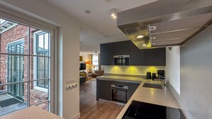 A modern kitchen with a built-in stove, a microwave, and a large window overlooking a brick building. - Wellness villa with sauna, garden and sea nearby (Colijnsplaat)