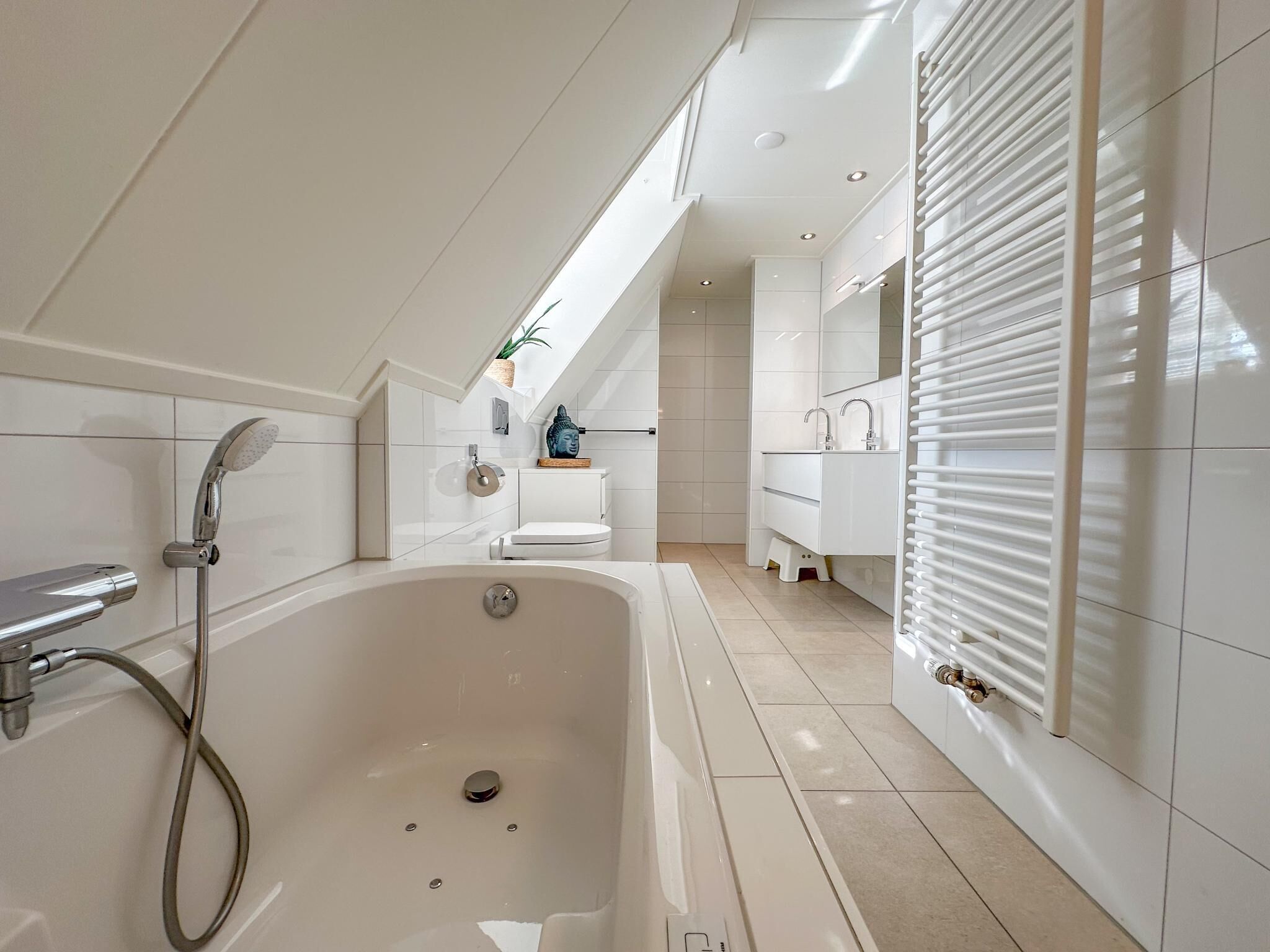 Een moderne badkamer met een vrijstaand bad, een toilet en een wastafel.