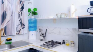 A modern kitchen with a sink, stove, and a water dispenser. - S&S APARTMENT #1 .3 MTS FROM FERRY (La Ceiba)