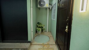 A narrow hallway with a black door, a small potted plant, and a ceiling fan. - S&S APARTMENT #1 .3 MTS FROM FERRY (La Ceiba)