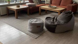 Un salon moderne avec un canapé, une table basse, un fauteuil poire et un tapis à motifs.