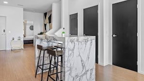 A modern kitchen with a marble island, bar stools, and a small seating area. - NEW! 1mi->Broadway! Top of the Tune Penthouse (Nashville)