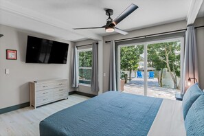 A bedroom with a bed, a ceiling fan, a TV, and a view of a water body and greenery outside. - Bay side, Park side, Beach Beach Beach (Indian Rocks Beach)