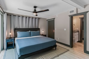 A bedroom with a bed, a ceiling fan, a nightstand, a lamp, a door, and a bathroom visible through an open door. - Bay side, Park side, Beach Beach Beach (Indian Rocks Beach)
