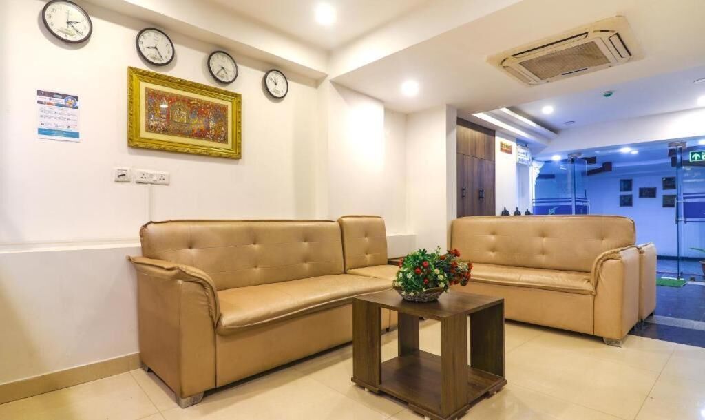 A reception area with two sofas, a small table with a flower arrangement, and clocks on the wall.