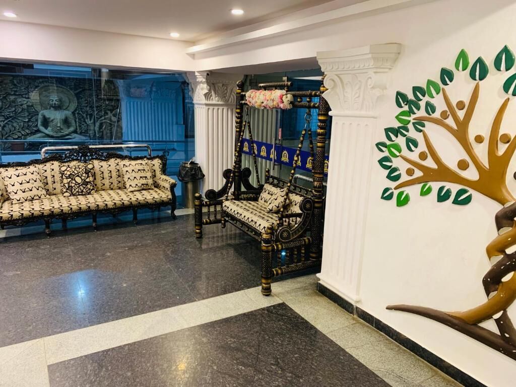A lobby with a patterned sofa, a decorative chair, and a wall mural.