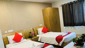 Ein Hotelzimmer mit zwei Betten, jeweils mit weißer Bettwäsche und roten Akzenten, einem Holzschrank und einem kleinen Tisch mit Blumen in einer Vase.