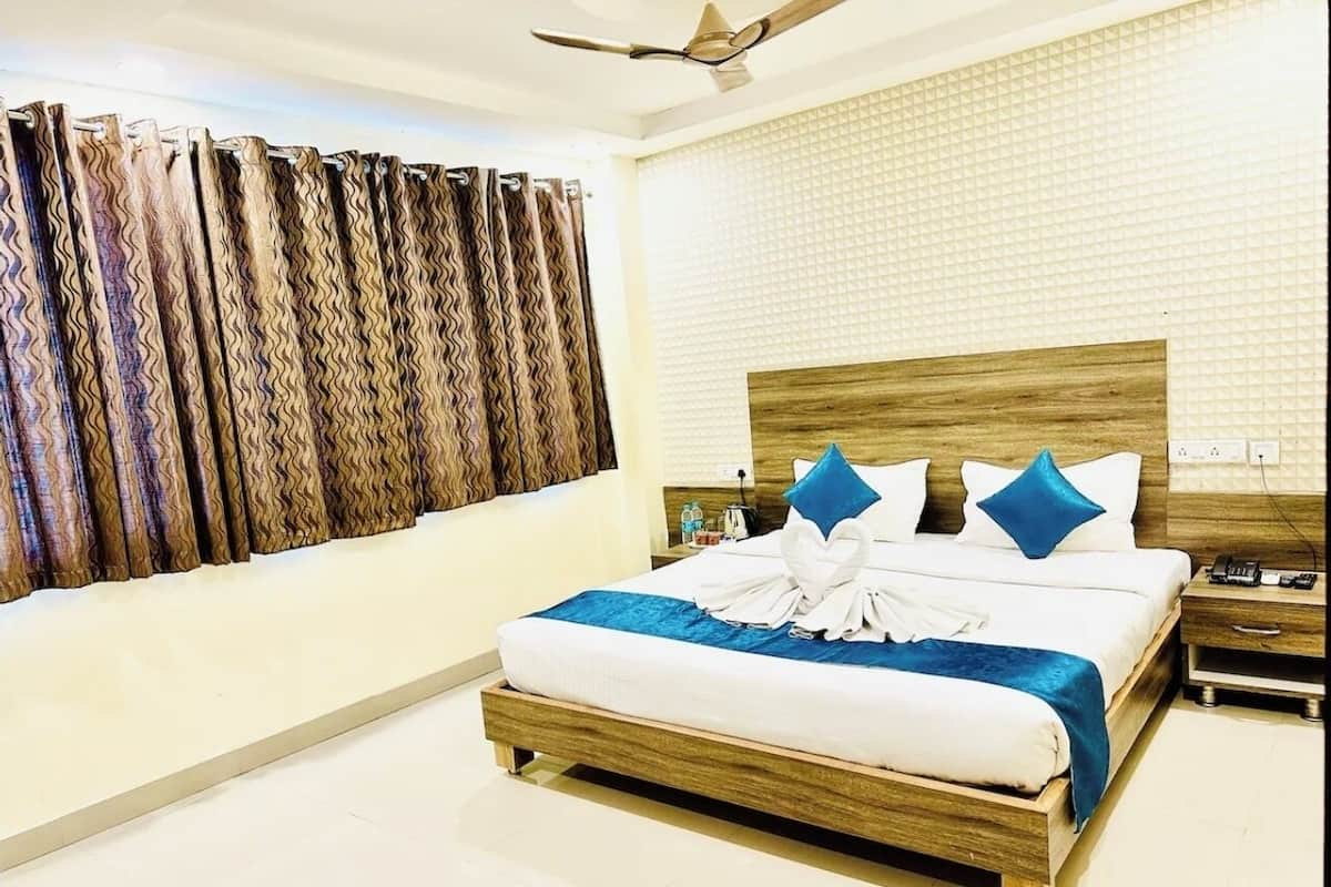 Habitación de hotel con una cama de madera, un cojín decorativo azul, un cojín blanco y una manta azul.
