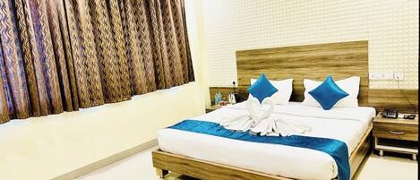 Habitación de hotel con una cama de madera, un cojín decorativo azul, un cojín blanco y una manta azul.