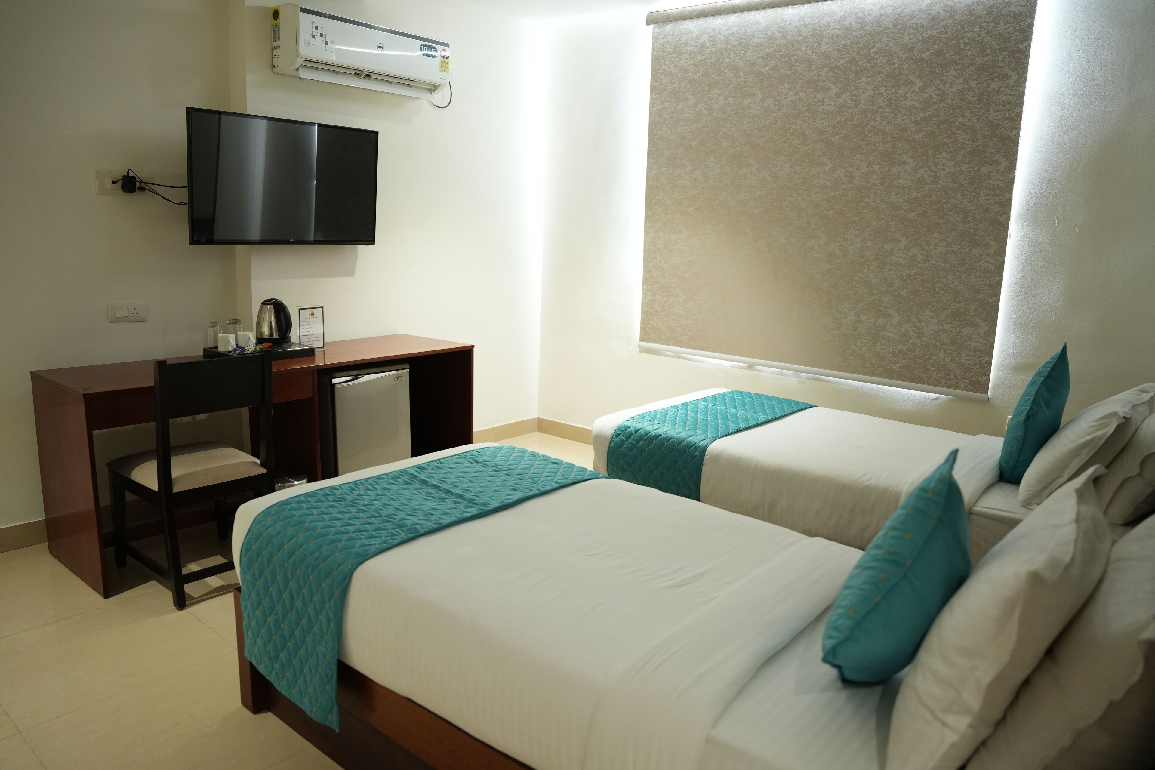 Une chambre d’hôtel avec deux lits, un bureau, une télévision et un appareil de climatisation.