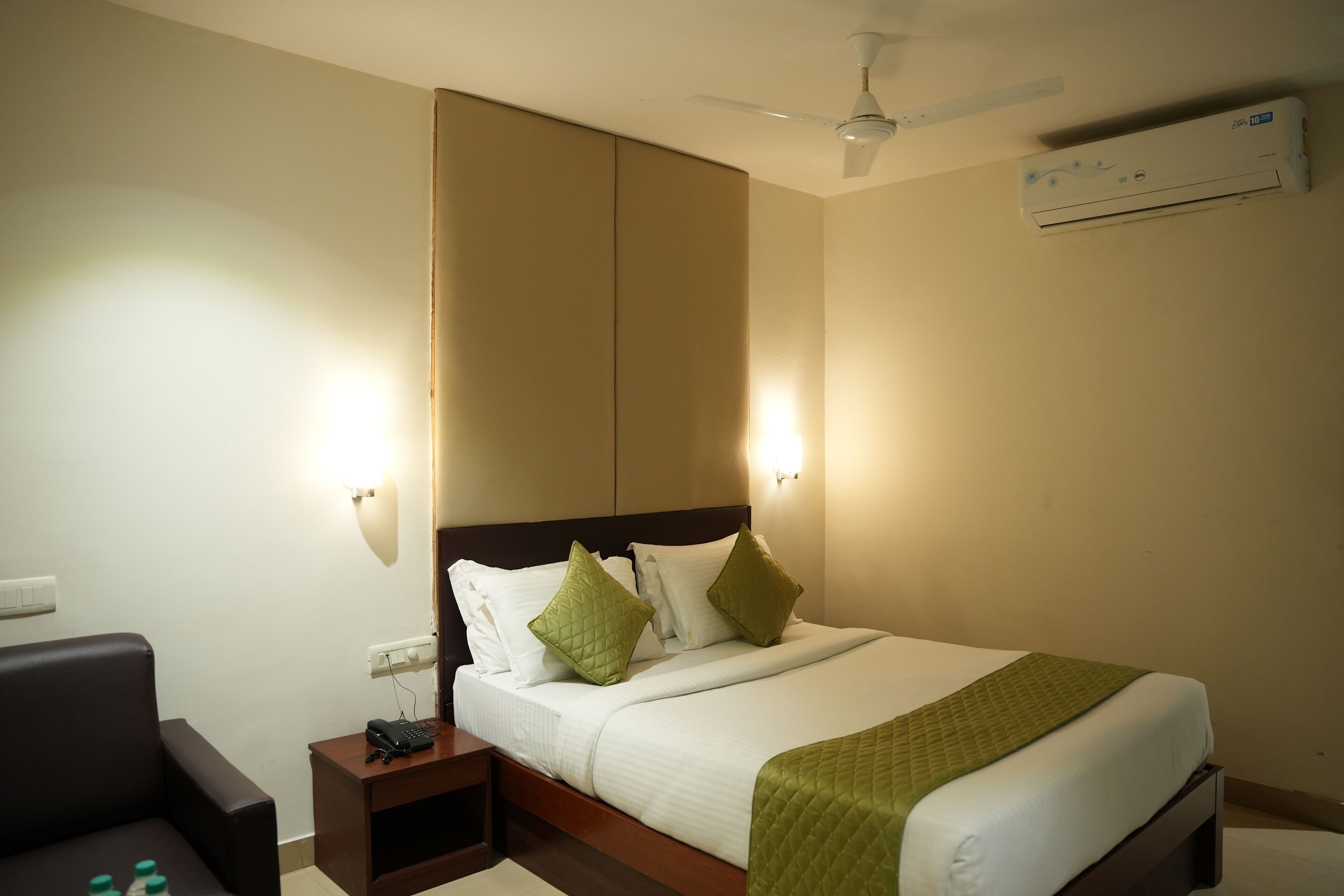 A hotel room with a bed, a desk, a chair, a phone, and a ceiling fan.