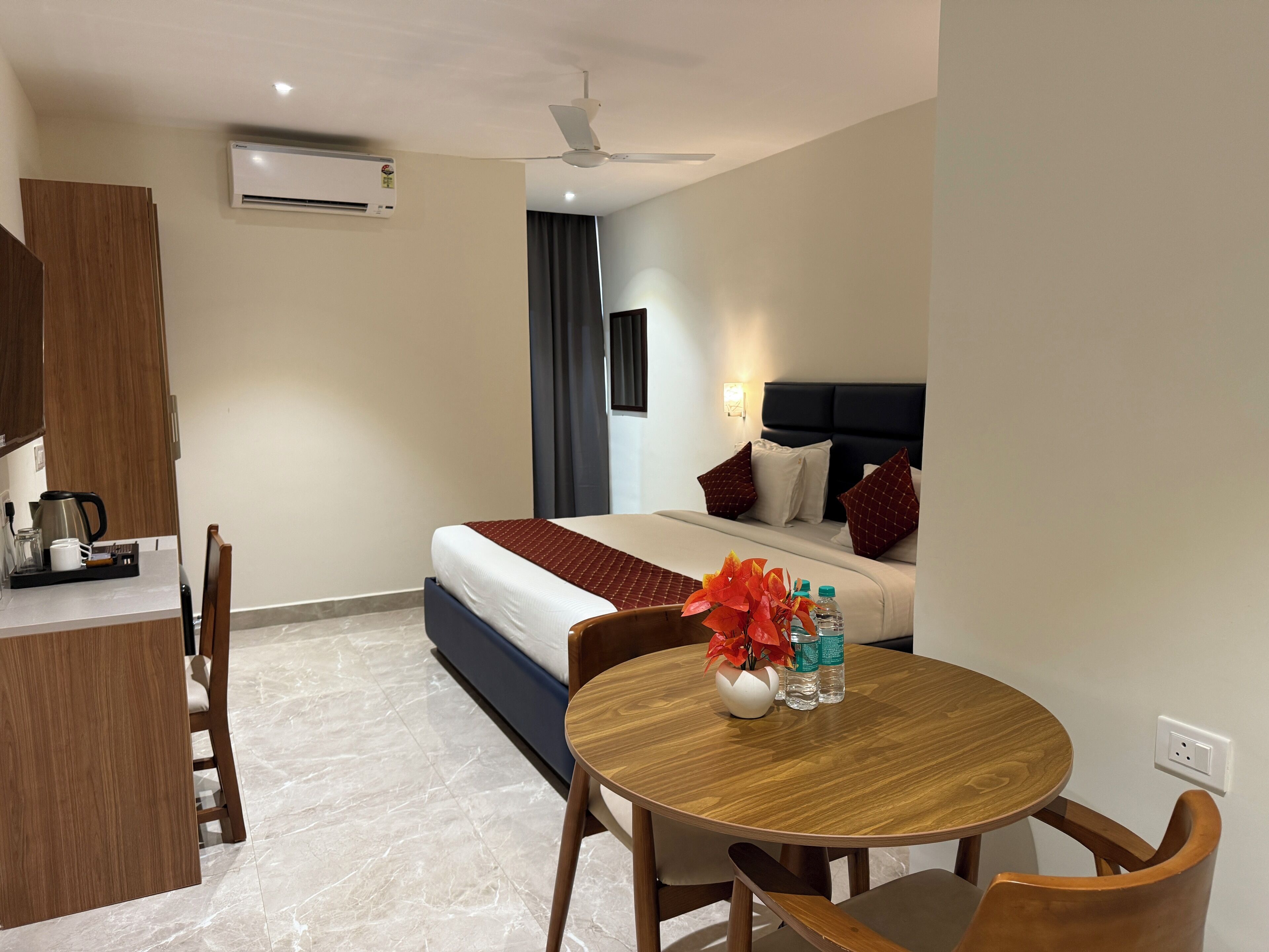 A hotel room with a bed, bedside table, and a small dining area with a table and chairs.