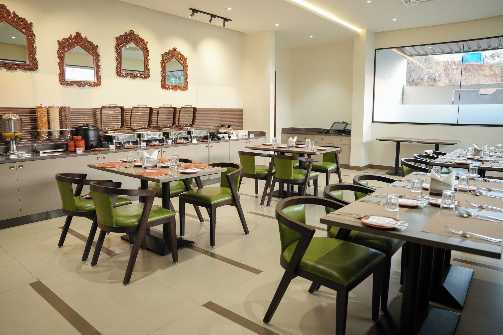 Un espace repas comprenant plusieurs tables et chaises, un buffet, et des miroirs décoratifs sur le mur.