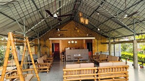 A spacious indoor area with a high ceiling, bamboo furniture, and a central seating area.