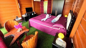 A hotel room with a bed, a desk, a chair, a wardrobe, and an air conditioning unit.