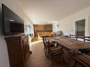 A modern living room with a flat-screen TV, wooden furniture, and a stone fireplace. - 120-square-meter vacation home with three separate bedrooms (Inzell)