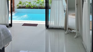 A spacious room with a large window, a white vanity, and a view of a swimming pool.