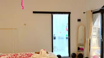 A hotel room with a bed, a large window, a mirror, and a hanging light fixture.