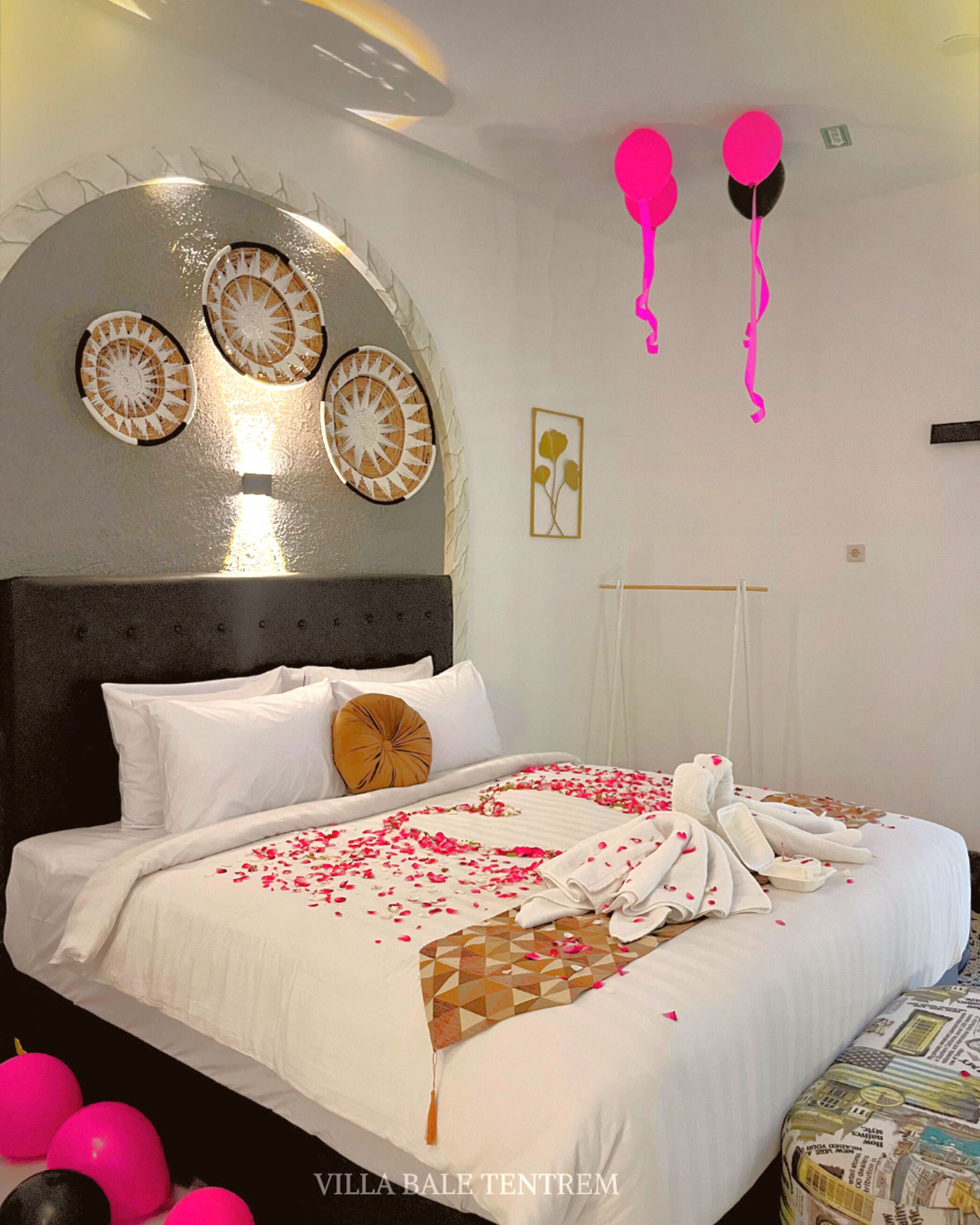 A hotel room with a large bed, decorative wall art, and a hanging light fixture.