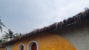 A building with a curved facade, three arched doorways, and a thatched roof.