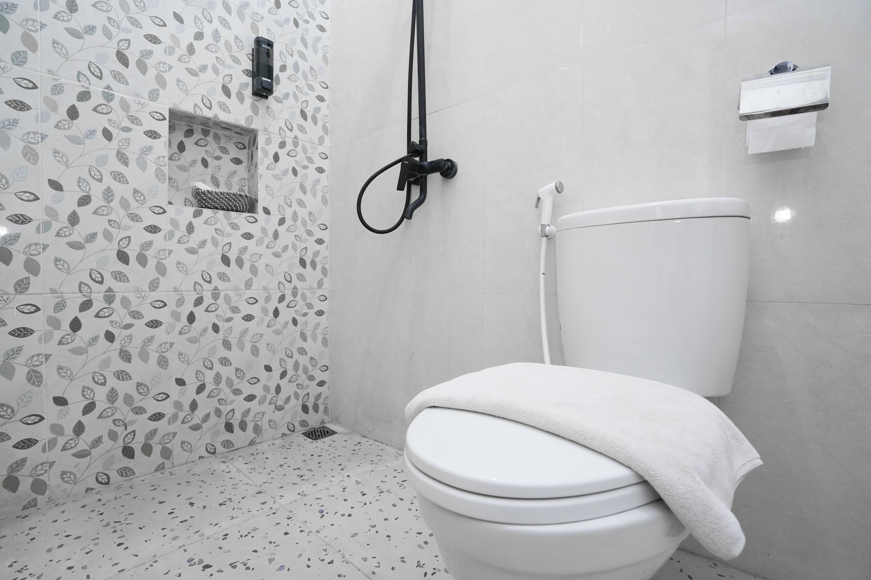 A bathroom with a toilet, shower, and a towel rack.