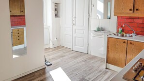 Een keuken met witte kasten, een rode bakstenen achterwand en een houten aanrecht.